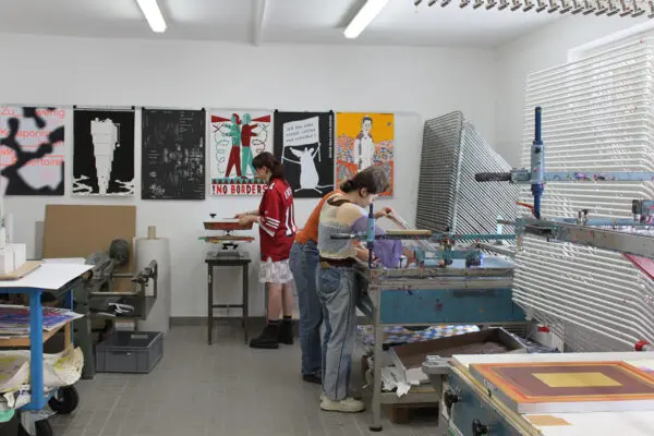 Three people working in a screen printing studio.