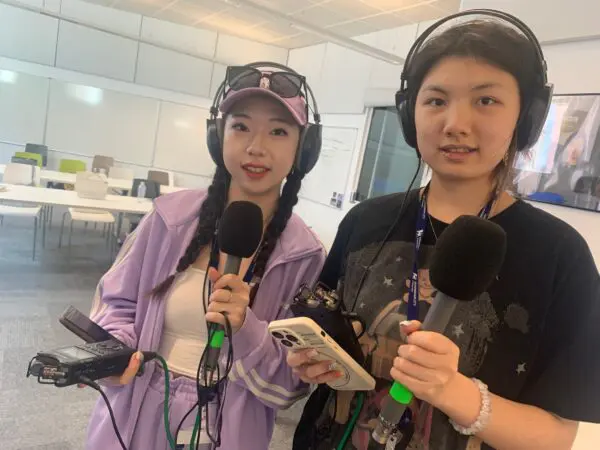 Two students hold microphones and recording equipment in a studio at Birmingham City University